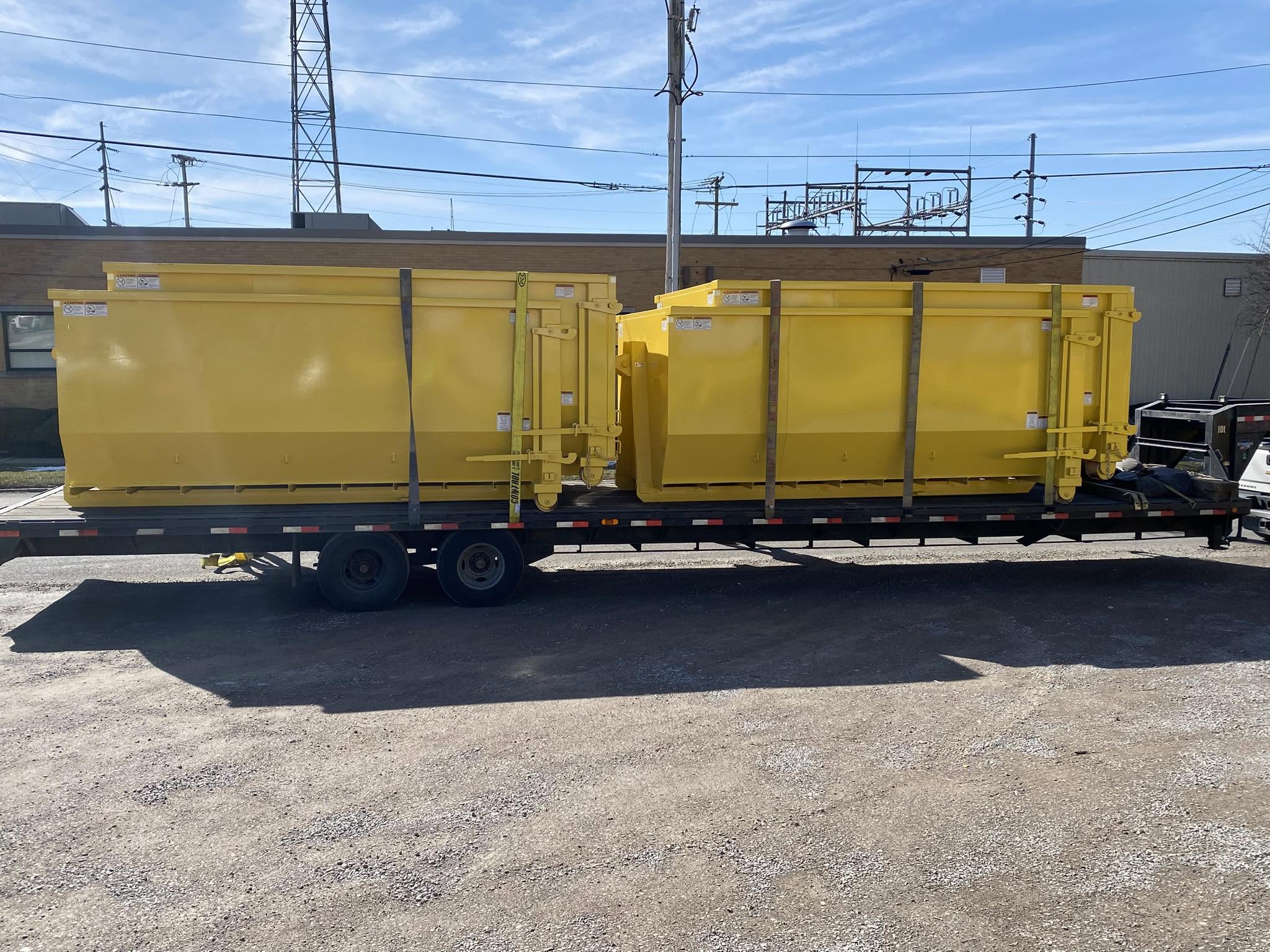 Black Tie Dumpsters roll-off dumpsters loaded on a delivery trailer
